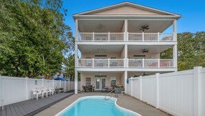 Un bâtiment à deux étages doté d’une piscine, de rampes blanches et d’un patio couvert.