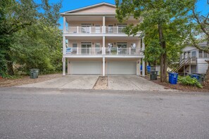 A two-story residential building with a garage, balconies, and a clear sky. - Nittany South, Luxury Rental, Block from Beach, Ocean View Balcony, Game Room (North Myrtle Beach)