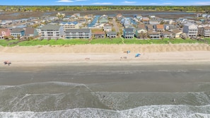 Un pueblo costero con propiedades frente a la playa, una playa de arena y vistas al océano.