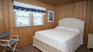 A wooden-paneled room with a single bed, a chair, and a window with blinds. - Nautical Winds, Beach House in Cherry Grove, Just Steps From the Beach (North Myrtle Beach)