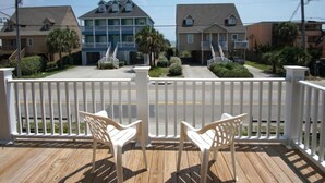 A wooden deck with two white chairs and a white picket fence. - Nautical Winds, Beach House in Cherry Grove, Just Steps From the Beach (North Myrtle Beach)