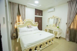 A bedroom with a large bed, a dresser, a mirror, and a wardrobe. - Prestige Resident Apartments and Homes (Abuja)