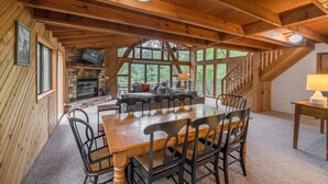 L’intérieur d’un chalet en bois comprend une table à manger, des chaises, une cheminée et un manteau de cheminée en pierre.