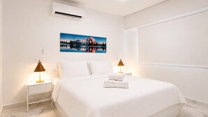 A hotel room with a bed, white walls, a painting, two bedside lamps, and a marble floor. - Jardines Apartment 1 (Puerto del Carmen)