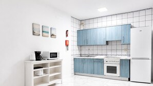 A modern kitchen with white cabinets, a white refrigerator, a microwave, a coffee maker, and a sink. There are three framed pictures on the wall. - Jardines Apartment 1 (Puerto del Carmen)