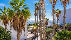 Una propiedad costera con palmeras, un edificio blanco y vistas al mar.
