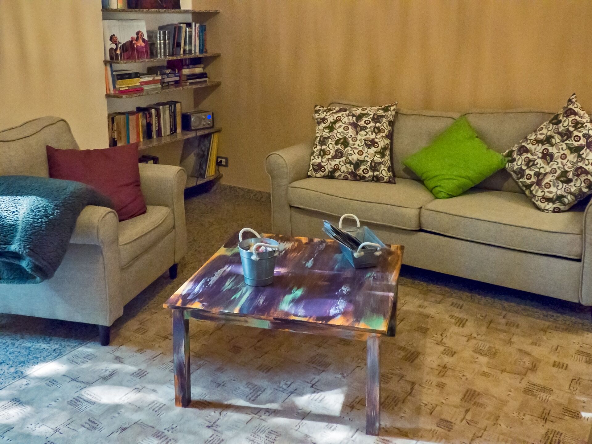 Un soggiorno con divano, tavolino, libreria e cuscini decorati.