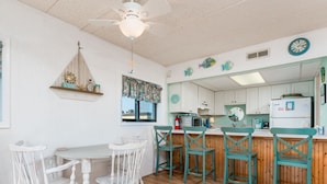 Une cuisine avec des meubles blancs, un plan de travail en bois et des chaises de couleur turquoise.