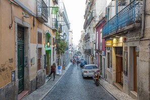 A narrow cobblestone street lined with buildings, some with balconies and signage. - Sunny Bairro Alto / Chiado Apt, by TimeCooler (Lisboa)