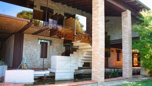 Un edificio con fachada de piedra, vigas de madera y una escalera que lleva a un nivel superior.