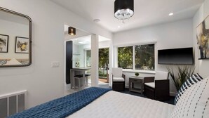 A modern bedroom with a large bed, a TV mounted on the wall, and a window providing a view of the outdoors. - Luxury Beach Studio — 2 blocks to the Beach and Funk Zone (Santa Barbara)