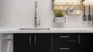 A modern kitchen with white subway tiles, stainless steel appliances, and black cabinets with gold handles. - Luxury Beach Studio — 2 blocks to the Beach and Funk Zone (Santa Barbara)