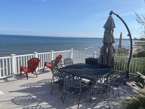 Une terrasse avec une table ronde et des chaises, donnant sur une étendue d’eau.