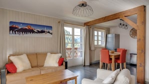 A cozy living room with a sofa, a wooden coffee table, and a dining area with a table and chairs. - Bright and spacious apartment close to city center (Châtel)