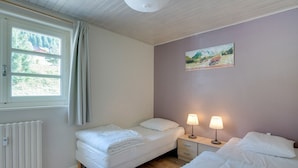 A bedroom with two beds, a radiator, a window with curtains, a nightstand with lamps, and a painting on the wall. - Bright and spacious apartment close to city center (Châtel)
