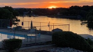 Zonsondergang boven een wateroppervlak met een zwembad en ligbedden.