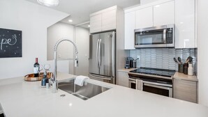 Een moderne keuken met roestvrijstalen apparatuur, een ingebouwde magnetron en een strakke achterwand.