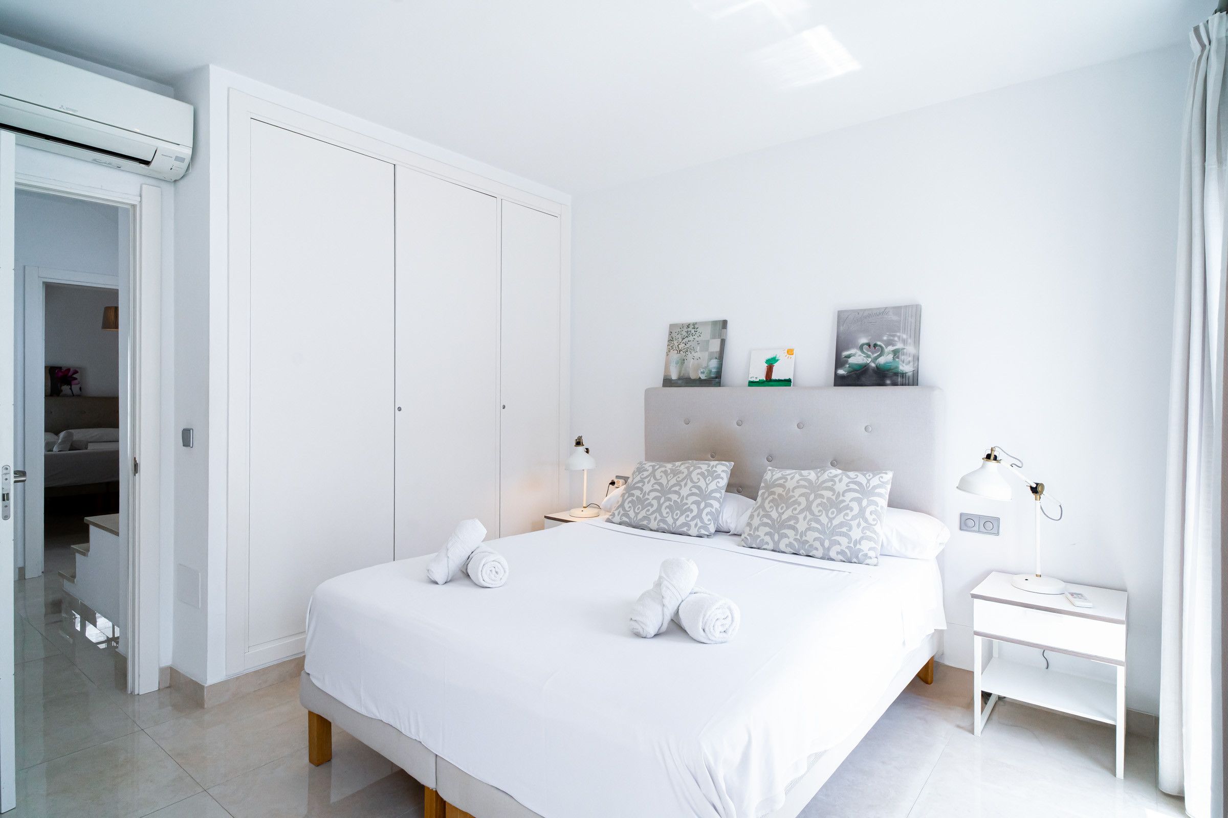 Een moderne slaapkamer met een groot bed, nachtlampjes en een nachtkastje.