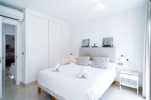 Een moderne slaapkamer met een groot bed, nachtlampjes en een nachtkastje.
