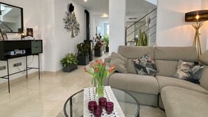 Ein modernes Wohnzimmer mit einer Couch, einem Couchtisch mit Kerzen und einer Treppe im Hintergrund.