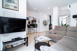 Een moderne woonkamer met een flatscreen televisie, een bank, een salontafel en een open haard.