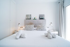 Une chambre moderne avec un grand lit, deux tables de chevet et des œuvres d’art accrochées au mur.
