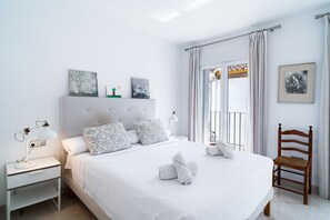 A hotel room with a bed, a nightstand, a chair, and artwork on the walls.