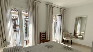 Ein Schlafzimmer mit einem großen Bett, einem Sessel, einem Schreibtisch und einem Spiegel.