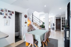 A modern dining area with a table, chairs, and a staircase leading to another level.