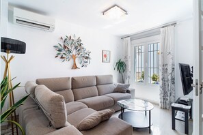 Un salon moderne avec un canapé, une table basse, une lampe et un arbre décoratif.