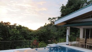 A swimming pool with a view of a house and surrounding greenery.