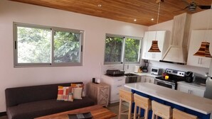 A modern kitchen with a wooden ceiling, white cabinets, and a central island with bar stools.