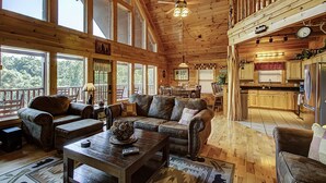 Ein geräumiges Blockhauskabinen-Interieur mit großem Wohnbereich, Holzböden und einer Küche.