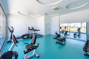 A gym with exercise equipment, large windows, and a view of the outdoors.