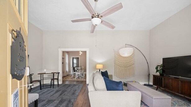 A living room with a ceiling fan, a television, and a dining area with a table and chairs. - Pet friendly 5 minute walk to Bath House! (Hot Springs)