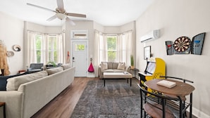 Un salon avec un canapé, un fauteuil, une petite table et un ventilateur de plafond.