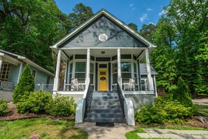 A two-story house with a front porch, a yellow door, and a staircase leading to the entrance. - Pet friendly 5 minute walk to Bath House! (Hot Springs)