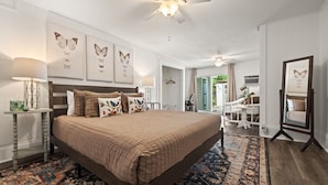 A bedroom with a large bed, a ceiling fan, and artwork on the walls. - Pet friendly 5 minute walk to Bath House! (Hot Springs)