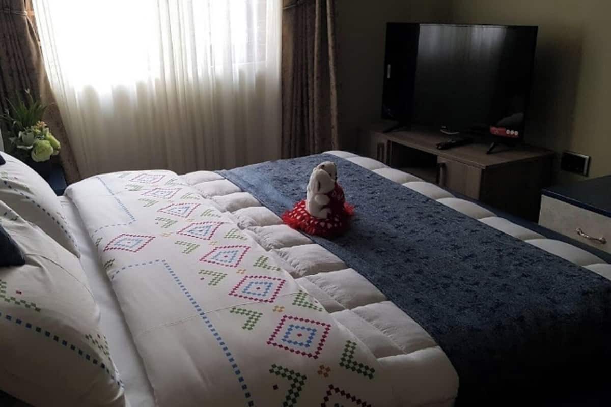 A hotel room with a bed, a television, and a small table.