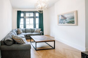 Relax in this stylish living room with a sofa, coffee table, and large windows.