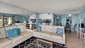 A living room with a sofa, coffee table, and a dining area with chairs and a table.