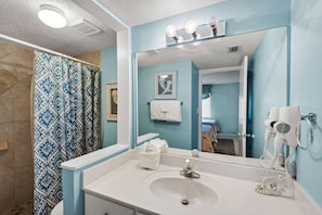 A bathroom with a large mirror, a sink, and a shower curtain. - Mariner by iTrip Panama City Beach (Panama City Beach)