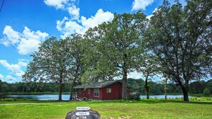 A red cabin by a lake with a sign indicating 'Inner/Outer Loop' and 'Powerline' paths.