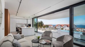 A modern apartment with a kitchen, living area, and a balcony with a city view.