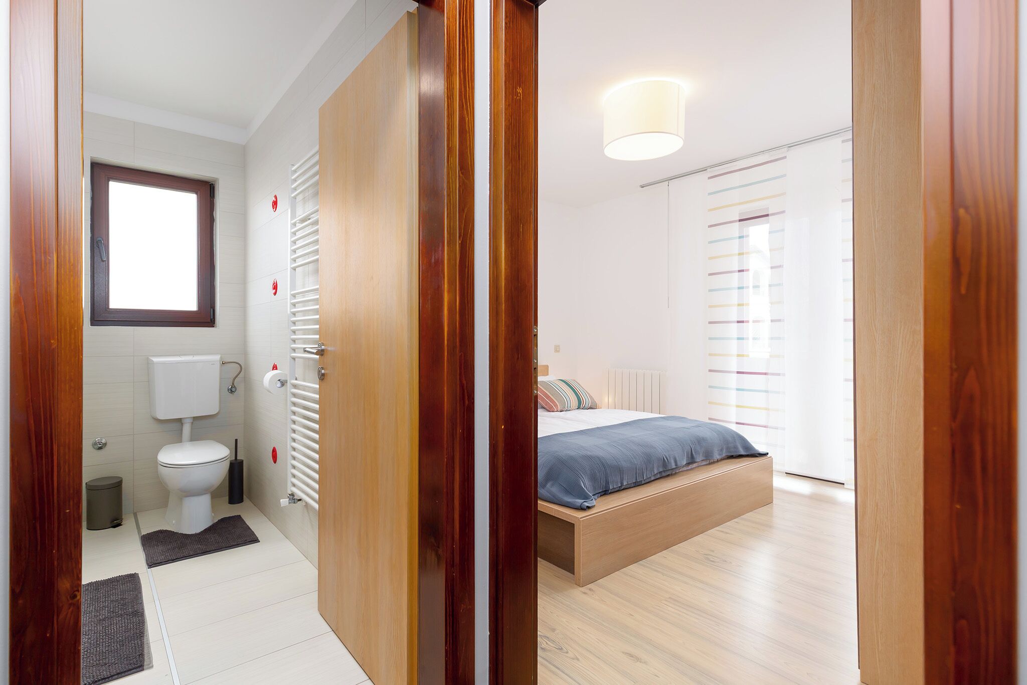 Una camera da letto con un letto di legno, una finestra, un termosifone e un gabinetto.