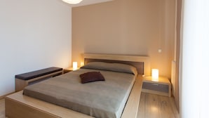Een moderne slaapkamer met een bed, nachtkastjes en een hanglamp.