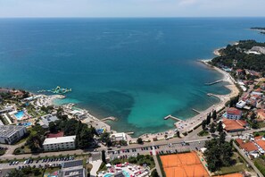 Vista aérea de un pueblo costero con playa, puerto deportivo y edificios.