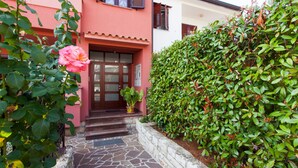 A house with a pink facade, a stone pathway leading to the entrance, and a rose bush in the foreground. - Apartment Mares Family 5+ 100m2 with parking and garden (Porec)