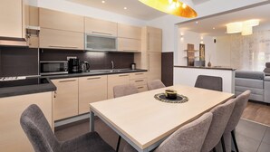 A modern kitchen with a dining area, featuring light wood cabinets, a microwave, and a dining table with chairs. - Apartment Mares Family 5+ 100m2 with parking and garden (Porec)