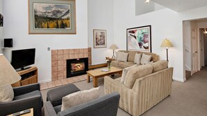 A living room with a fireplace, sofas, a television, and artwork on the walls.